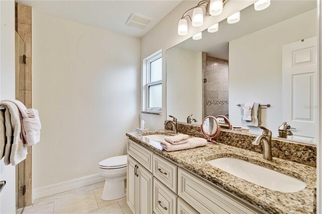 full bath featuring a stall shower, toilet, double vanity, and baseboards