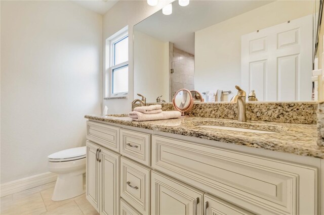 full bathroom with toilet, tiled shower, baseboards, double vanity, and tile patterned floors