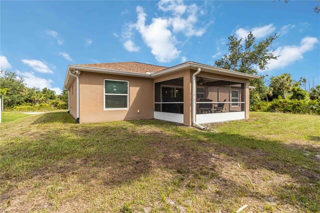 back of property featuring a sunroom, a lawn, and stucco siding