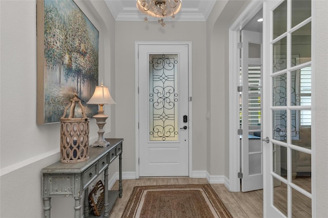 entryway featuring crown molding, light wood-style flooring, baseboards, and an inviting chandelier