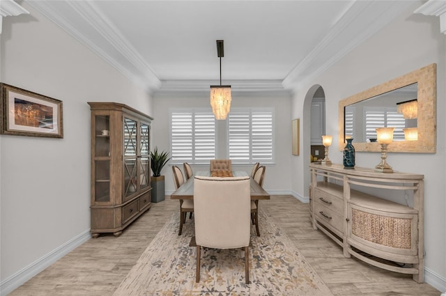 dining area featuring light wood-style floors, arched walkways, baseboards, and ornamental molding