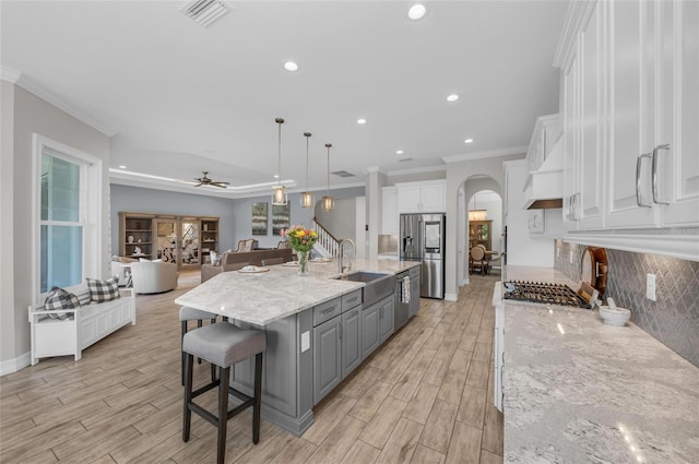 kitchen with visible vents, gray cabinets, arched walkways, a sink, and appliances with stainless steel finishes
