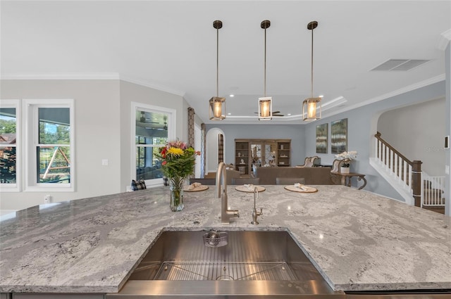 kitchen featuring a sink, arched walkways, crown molding, and visible vents