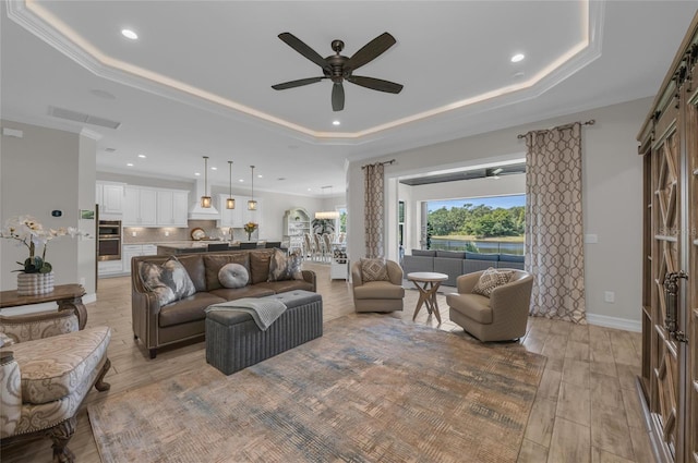 living area featuring light wood finished floors, a ceiling fan, a tray ceiling, and recessed lighting