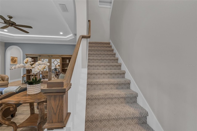 stairway featuring a raised ceiling, a ceiling fan, baseboards, recessed lighting, and visible vents