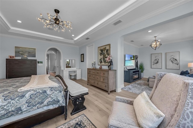 bedroom featuring an inviting chandelier, visible vents, light wood-style floors, a raised ceiling, and arched walkways