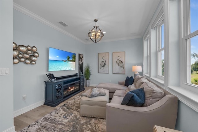 living area with a notable chandelier, baseboards, wood finished floors, visible vents, and ornamental molding