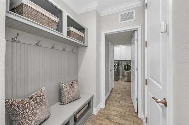 mudroom with visible vents, crown molding, washing machine and dryer, baseboards, and light wood-style flooring
