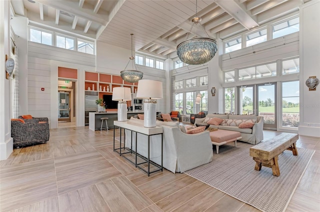 living room featuring an inviting chandelier, a high ceiling, beam ceiling, and a wealth of natural light