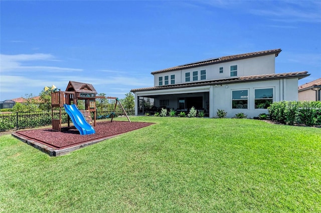 rear view of property featuring fence, playground community, stucco siding, a lawn, and a tiled roof