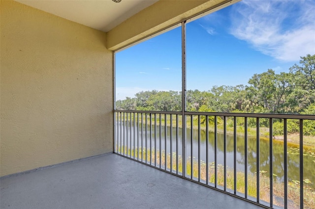 balcony with a water view and view of wooded area
