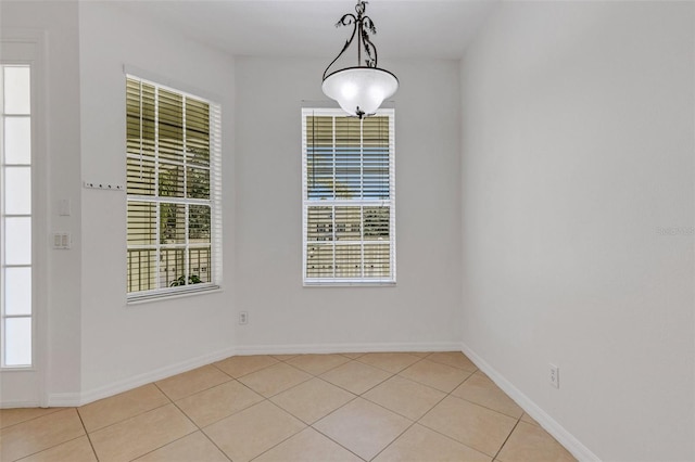 unfurnished dining area with light tile patterned floors and baseboards