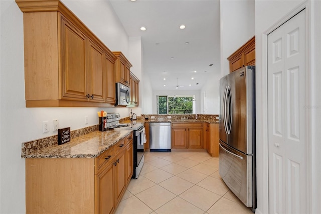 kitchen featuring stainless steel appliances, a sink, stone countertops, light tile patterned flooring, and recessed lighting