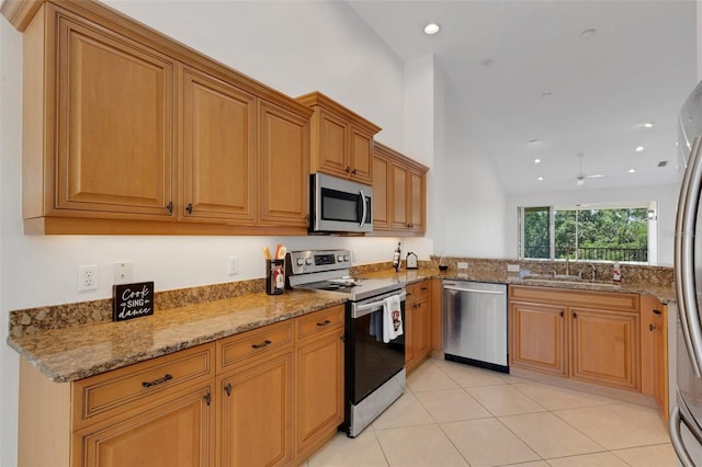 kitchen featuring appliances with stainless steel finishes, a sink, light stone counters, a ceiling fan, and recessed lighting