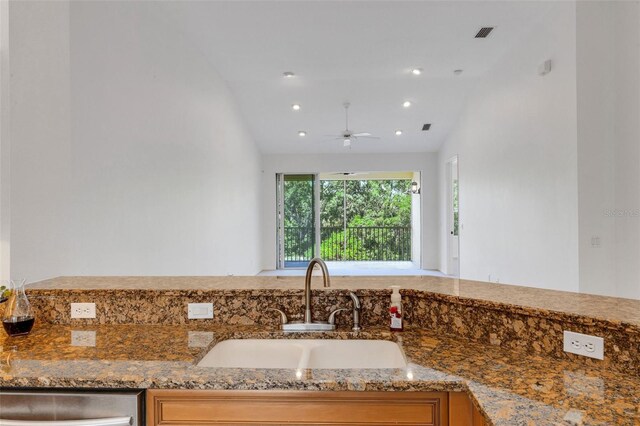 kitchen with lofted ceiling, ceiling fan, dark stone counters, a sink, and dishwasher