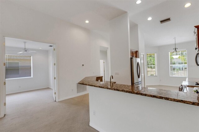 kitchen featuring freestanding refrigerator, light carpet, recessed lighting, dark stone counters, and baseboards