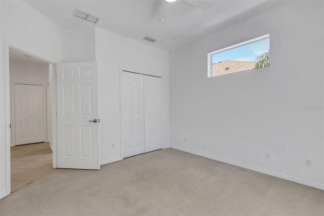 unfurnished bedroom featuring carpet, baseboards, a closet, and a ceiling fan