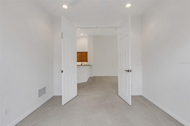 spare room featuring light carpet, recessed lighting, and baseboards