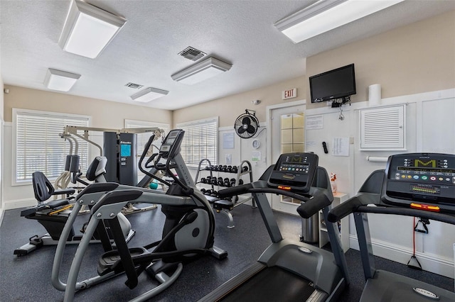 exercise room with a textured ceiling and baseboards