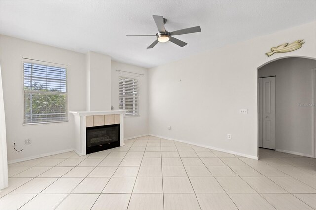 12014 Beeflower Dr, Lakewood Ranch, FL 34202 - unfurnished living room featuring a tiled fireplace, a ceiling fan, baseboards, and light tile patterned floors