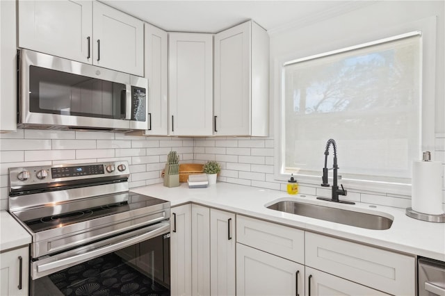 578-580 Companion Way, Longboat Key, FL 34228 - kitchen with white cabinetry, decorative backsplash, a sink, stainless steel appliances, and light countertops