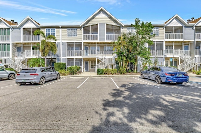 view of building exterior featuring stairway and uncovered parking