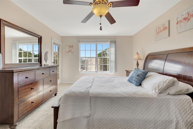 bedroom featuring light carpet, baseboards, a ceiling fan, and multiple windows