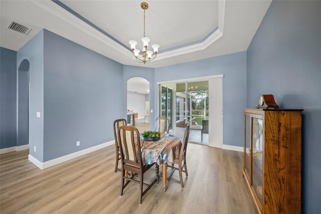 9106 Yarberry St, Sarasota, FL 34240 - dining area featuring an inviting chandelier, wood finished floors, visible vents, a raised ceiling, and arched walkways