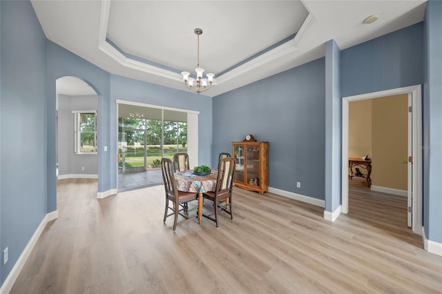 9106 Yarberry St, Sarasota, FL 34240 - dining area featuring light wood-style flooring, a tray ceiling, baseboards, a chandelier, and arched walkways