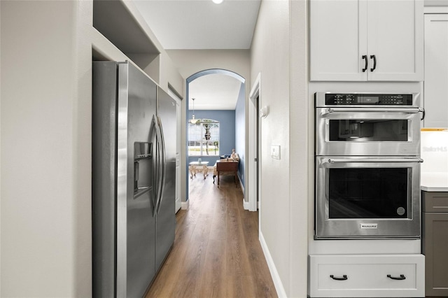 9106 Yarberry St, Sarasota, FL 34240 - kitchen featuring wood finished floors, stainless steel appliances, baseboards, arched walkways, and light countertops