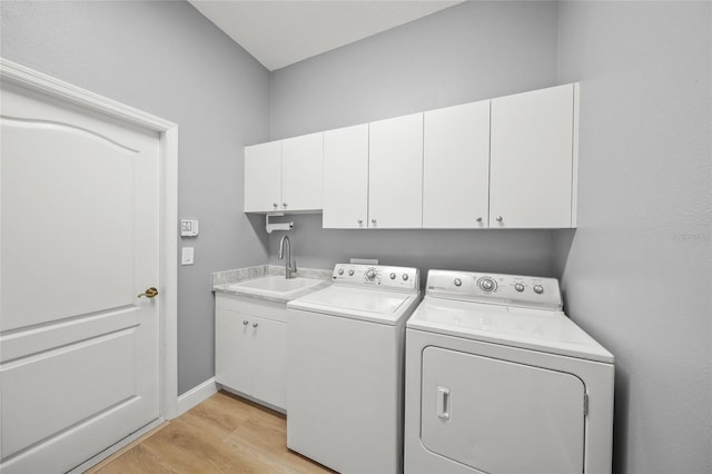 9106 Yarberry St, Sarasota, FL 34240 - clothes washing area featuring baseboards, light wood finished floors, a sink, washing machine and clothes dryer, and cabinet space