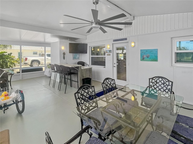 dining space featuring a ceiling fan, concrete flooring, and lofted ceiling