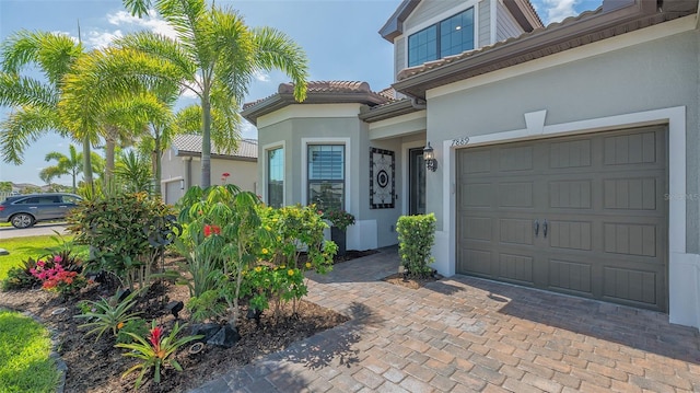 7889 Mainsail Ln, Sarasota, FL 34240 - doorway to property featuring a garage, stucco siding, a tiled roof, and decorative driveway