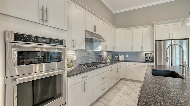 7889 Mainsail Ln, Sarasota, FL 34240 - kitchen with appliances with stainless steel finishes, under cabinet range hood, light marble finish flooring, a sink, and white cabinets