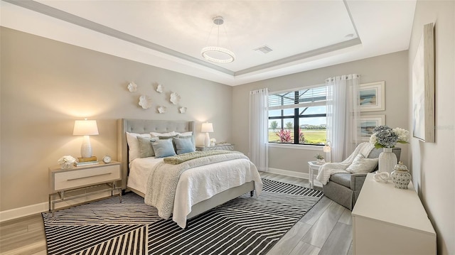 7889 Mainsail Ln, Sarasota, FL 34240 - bedroom with a tray ceiling, baseboards, and light wood-style flooring