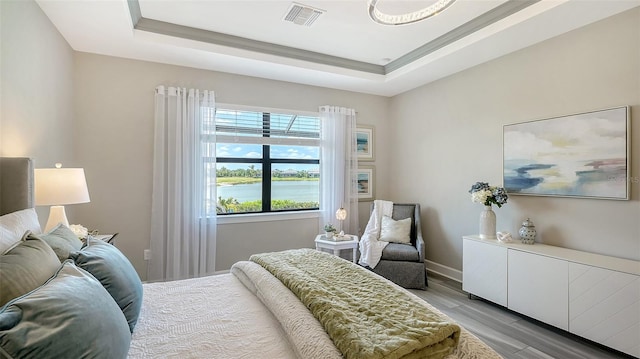 7889 Mainsail Ln, Sarasota, FL 34240 - bedroom featuring light wood-style flooring, a raised ceiling, baseboards, and a water view