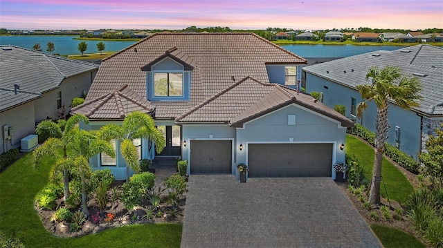 7889 Mainsail Ln, Sarasota, FL 34240 - mediterranean / spanish-style home with a tiled roof, a garage, a water view, decorative driveway, and stucco siding