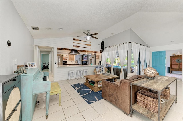 living area with a textured ceiling, a ceiling fan, light tile patterned floors, lofted ceiling, and visible vents