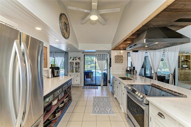 kitchen with wall chimney range hood, appliances with stainless steel finishes, a sink, light stone counters, and white cabinetry