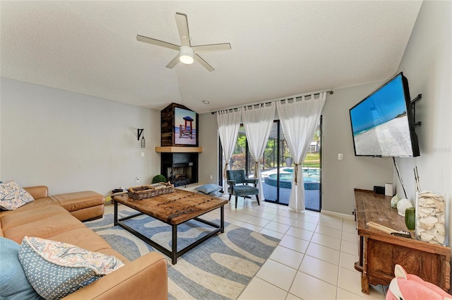 living area with lofted ceiling, a fireplace, baseboards, a ceiling fan, and light tile patterned floors