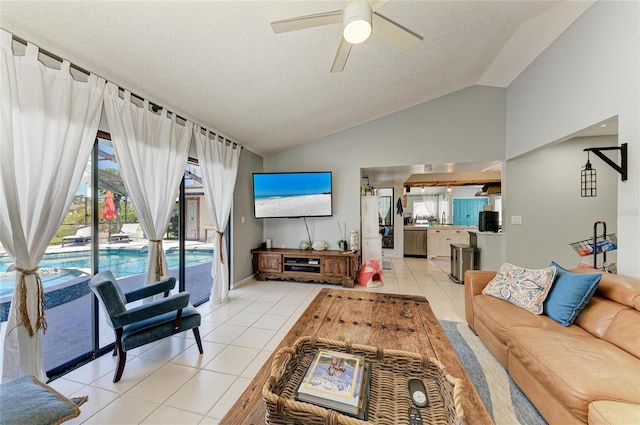 living area with a textured ceiling, a ceiling fan, light tile patterned flooring, and lofted ceiling