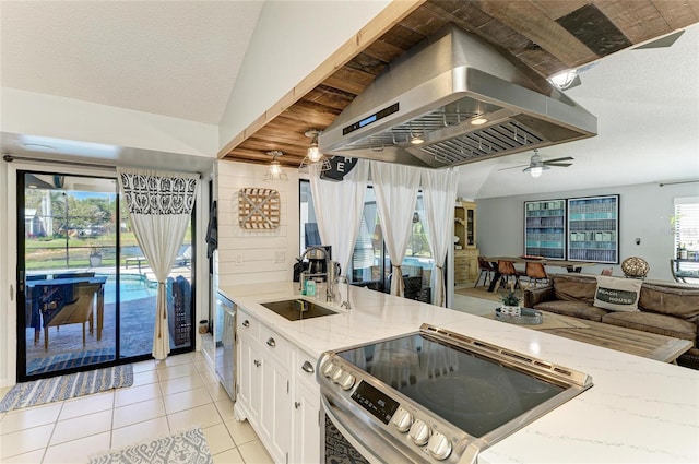 kitchen with light stone countertops, island range hood, a sink, appliances with stainless steel finishes, and light tile patterned floors