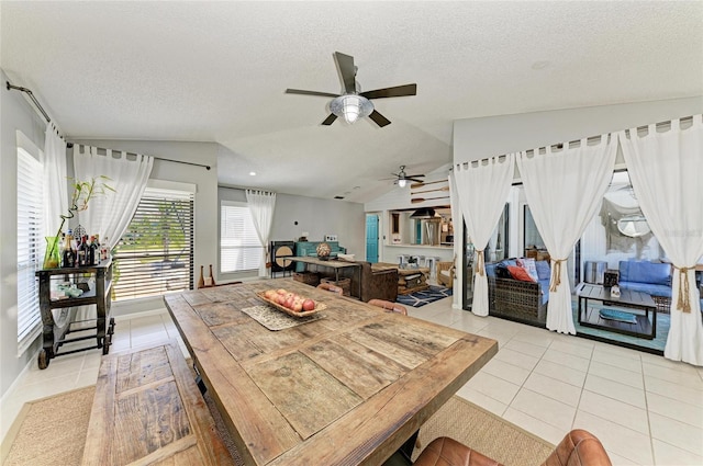 dining area with a textured ceiling, ceiling fan, light tile patterned floors, and lofted ceiling