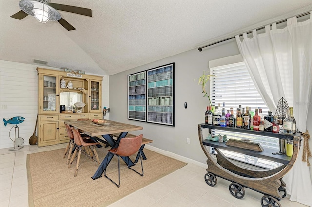 dining space featuring ceiling fan, a textured ceiling, visible vents, light tile patterned floors, and lofted ceiling
