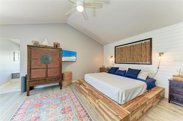 bedroom with wooden walls, a ceiling fan, vaulted ceiling, and wood finished floors