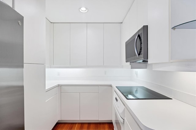 2918 Avenue Ave E, Holmes Beach, FL 34217 - kitchen with stainless steel microwave, oven, black electric cooktop, light countertops, and white cabinets