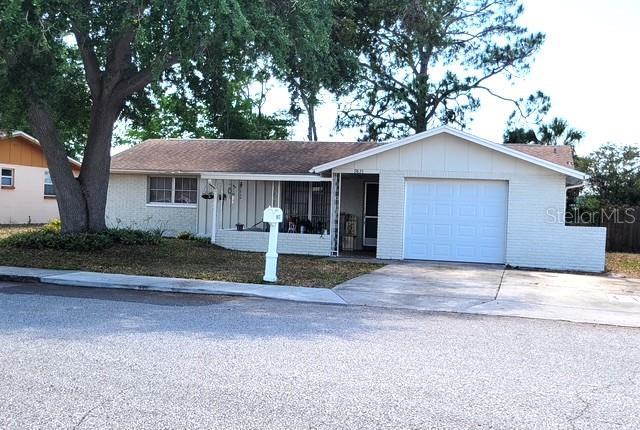 9835 El Camino Real Ave, Port Richey, FL 34668 - ranch-style house featuring brick siding, board and batten siding, an attached garage, and concrete driveway
