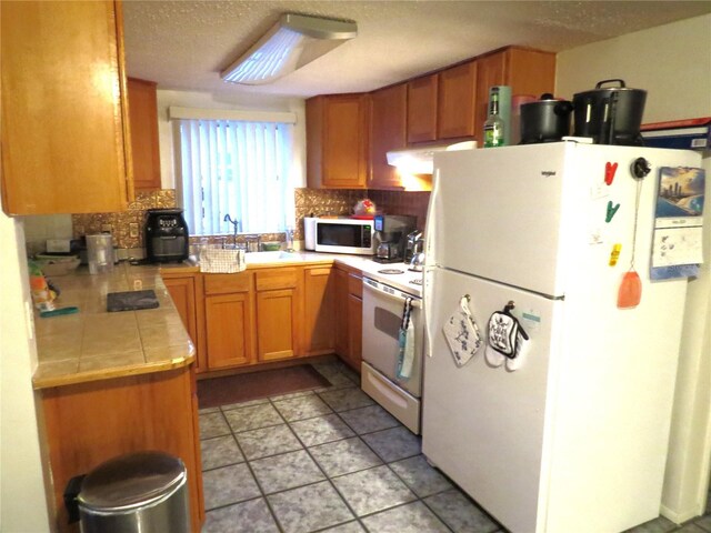9835 El Camino Real Ave, Port Richey, FL 34668 - kitchen featuring white appliances, a sink, tasteful backsplash, tile countertops, and a textured ceiling