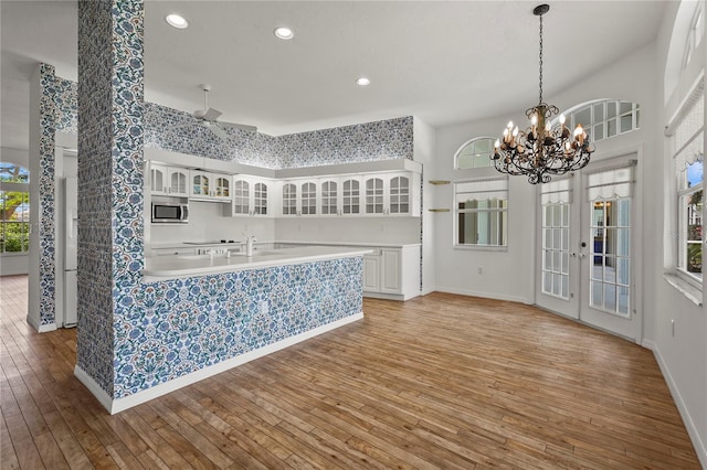 4180 Via Mirada, Sarasota, FL 34238 - kitchen featuring glass insert cabinets, white cabinets, stainless steel microwave, light wood-type flooring, and light countertops
