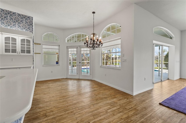4180 Via Mirada, Sarasota, FL 34238 - unfurnished dining area with a chandelier, baseboards, light wood-style floors, french doors, and a towering ceiling